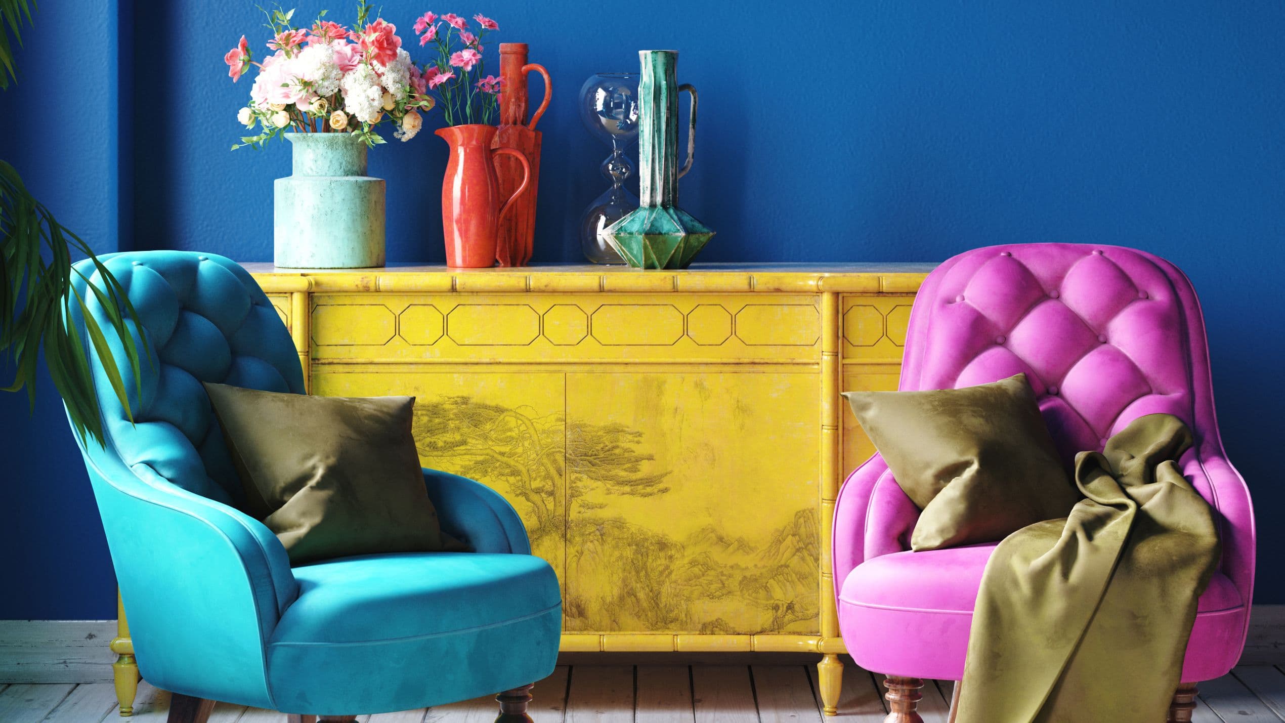 Bunte Sessel vor gelber Kommode.