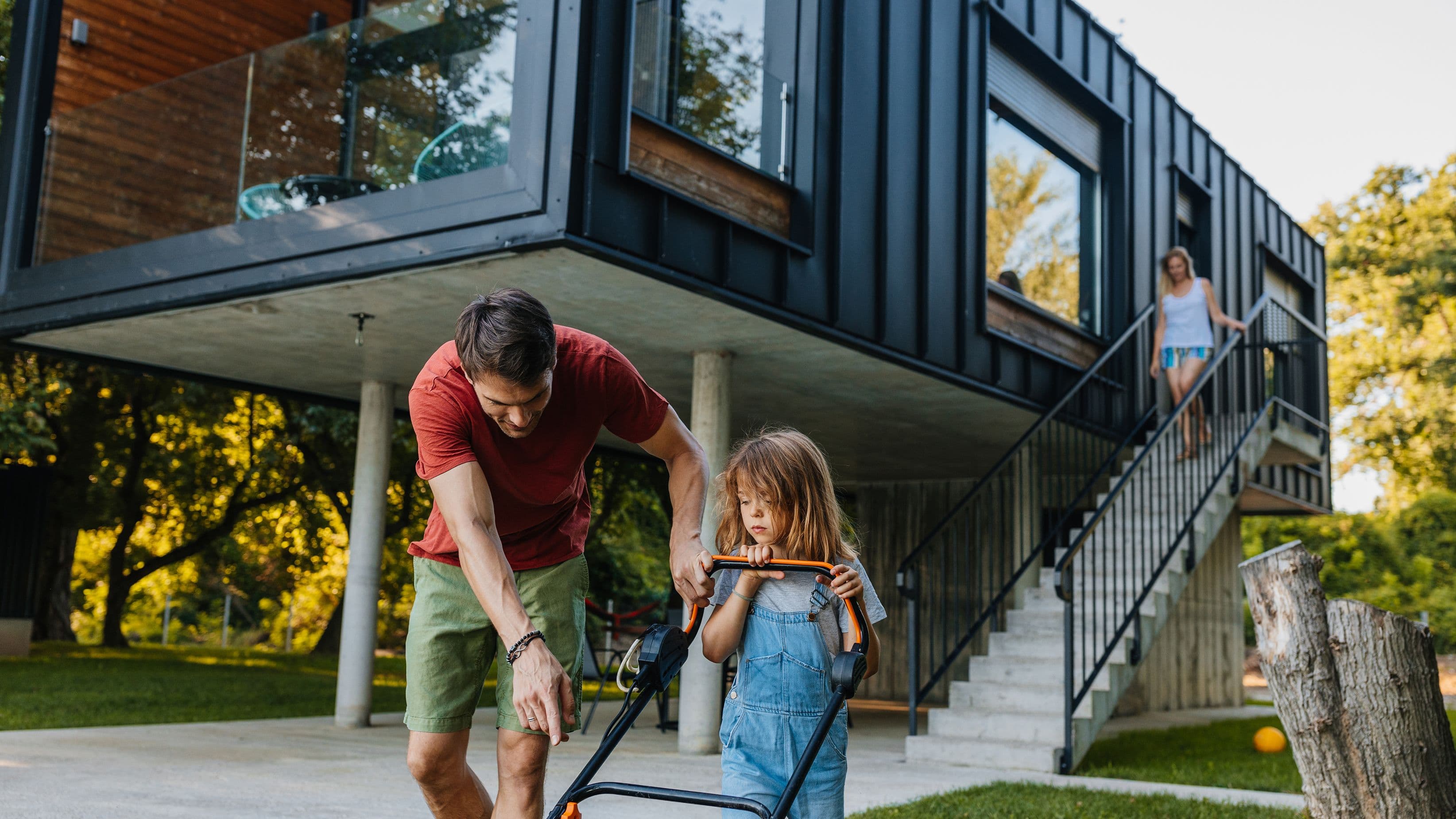 Vater und Tochter mähen Rasen.