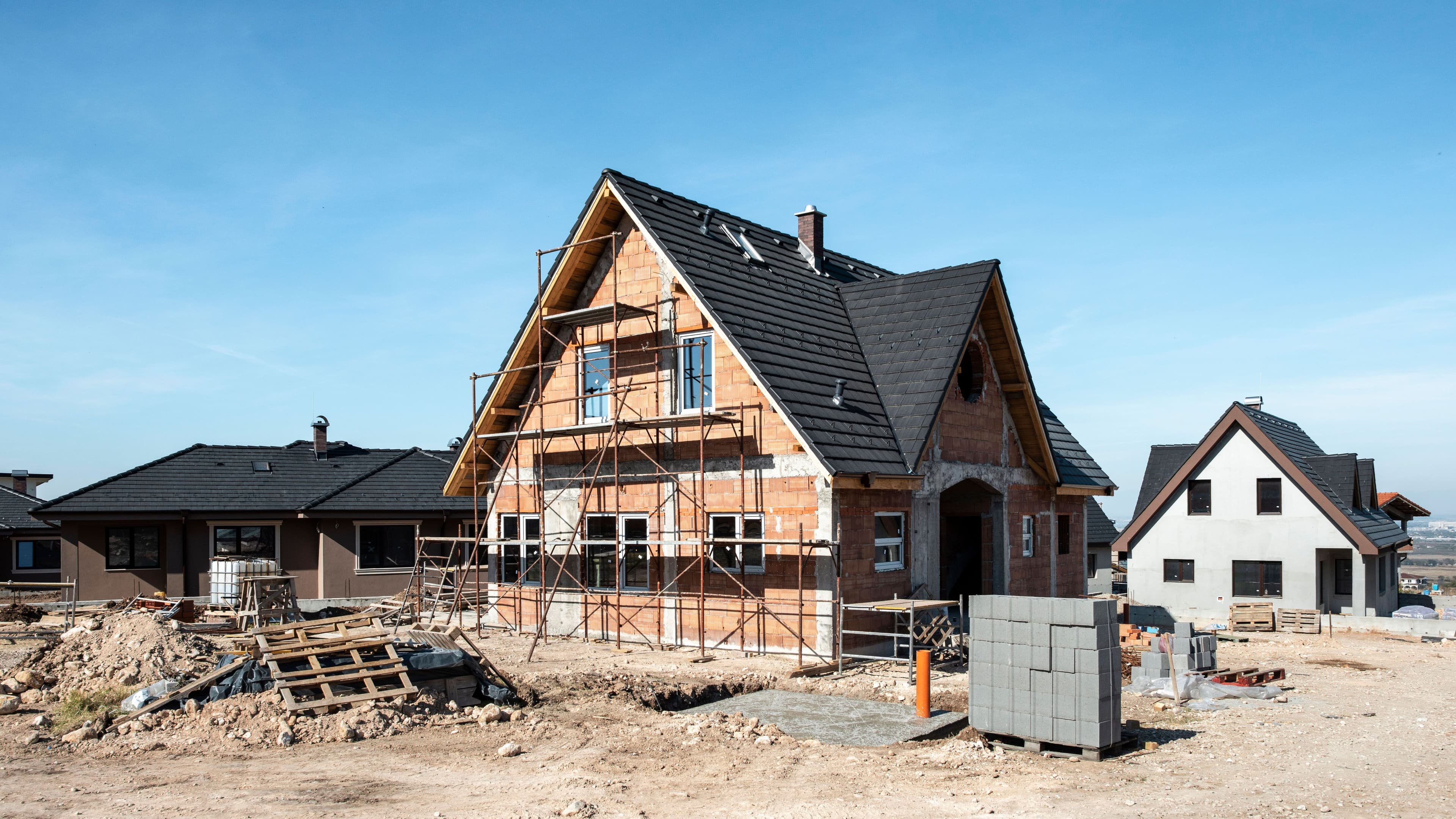 Ein Einfamilienhaus in einer Neubausiedlung. Es ist eingerüstet.